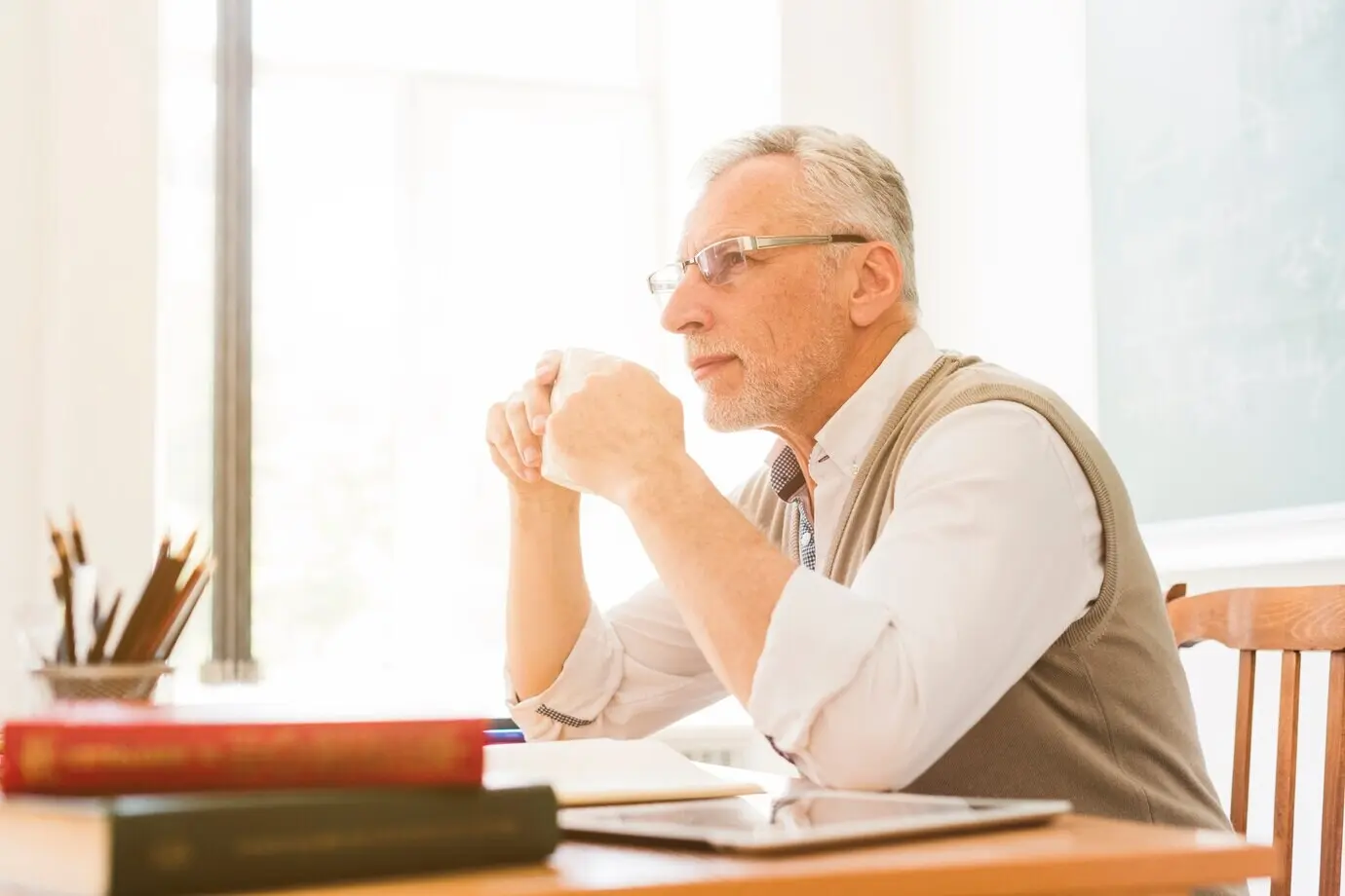 An elderly teacher drinking in a classroom