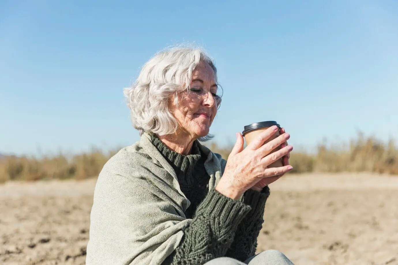 A beautiful elderly woman holding coffee.